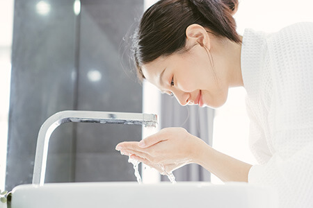 Woman Washing Face in Sink